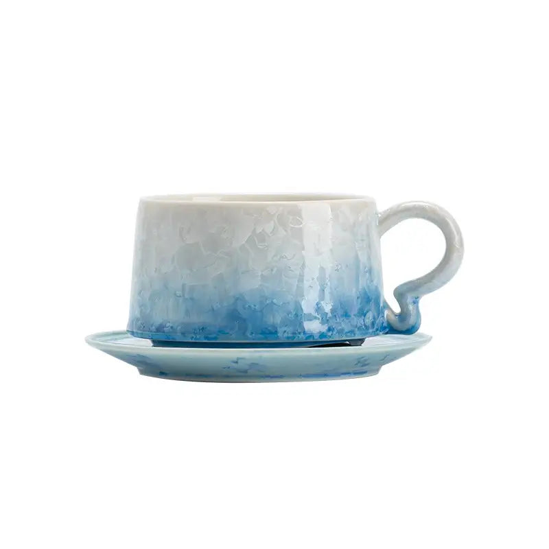 Blue and white ceramic coffee cup with matching saucer featuring Tenmoku glaze detail