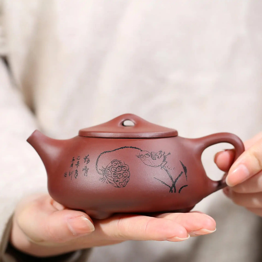 Maroon clay teapot with etched design.