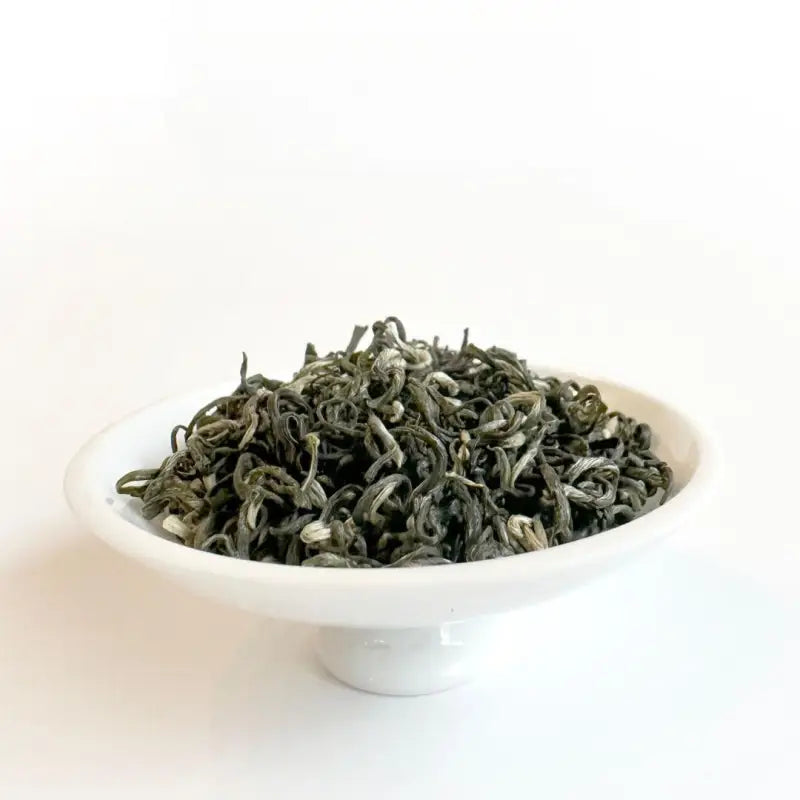Green tea leaves in a white bowl showcasing 2025 First Harvest Biluochun Green Tea