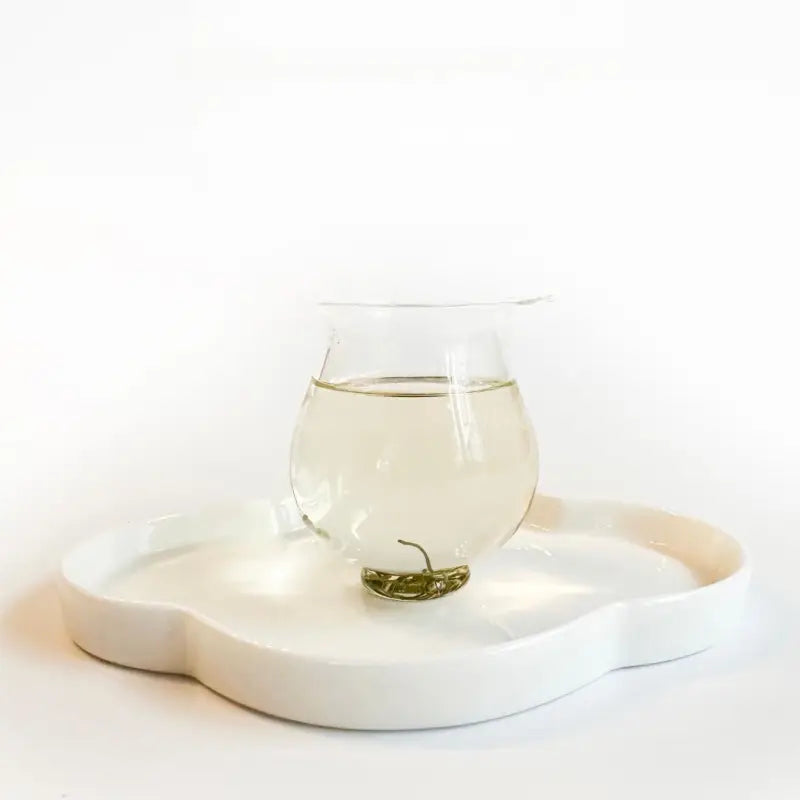 Clear glass of green tea on white tray showcasing 2025 First Harvest Biluochun Green Tea