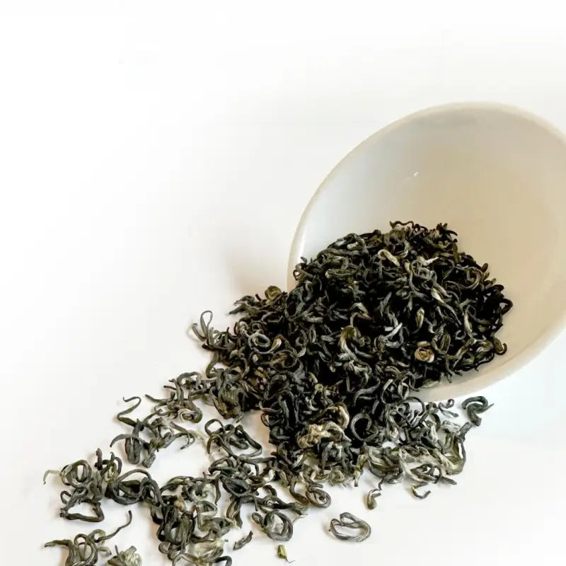 Green tea leaves spilling from a white bowl, premium 2025 First Harvest Biluochun Green Tea