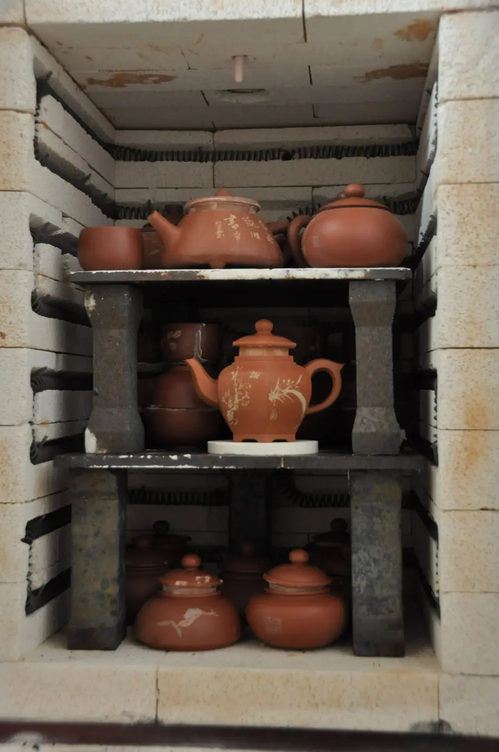 Théières et tasses en terre cuite sur des étagères présentant la poterie Jianshui Zitao avec technique d'incrustation et argile à cinq couleurs