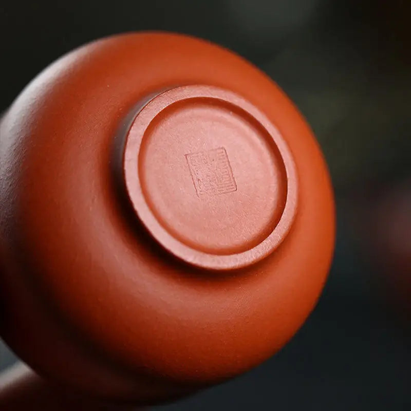 Reddish-brown ceramic cup bottom from Amber, showcasing authentic Yixing Zisha craftsmanship