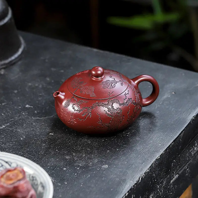 Reddish-brown round teapot with floral design from Ancient Plum Tree Yixing Zisha collection