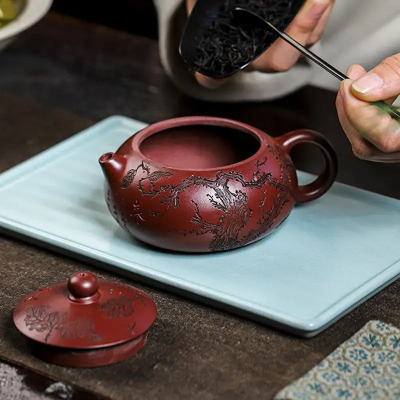 Reddish-brown Yixing Zisha teapot with intricate Ancient Plum Tree engravings