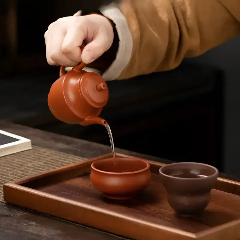 Earthenware teapot pouring tea from Autumn Square Yixing Zisha teapot set