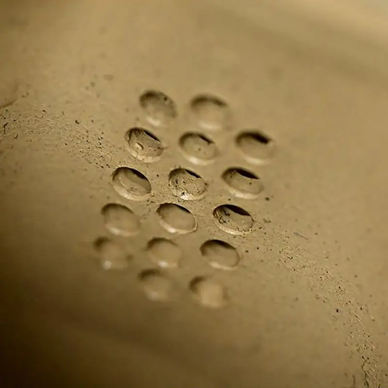 Perforated metal surface featuring Bamboo Flow design with yixing duanni and duanni clay elements