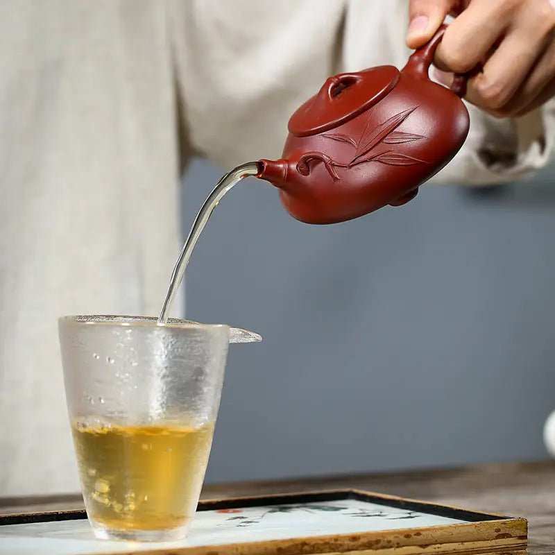 Red clay teapot pouring tea from Bamboo Segment, ideal for traditional tea sets and mugs