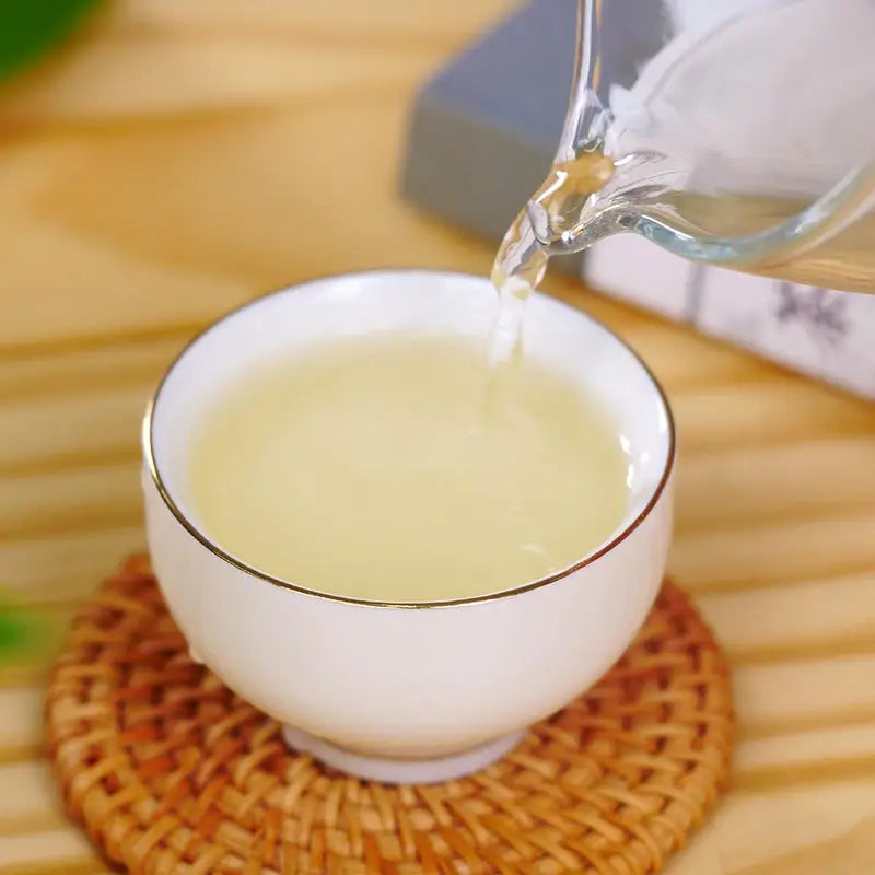 White tea cup being filled with Bi Luo Chun Green Tea Leaves in a stylish mug shot