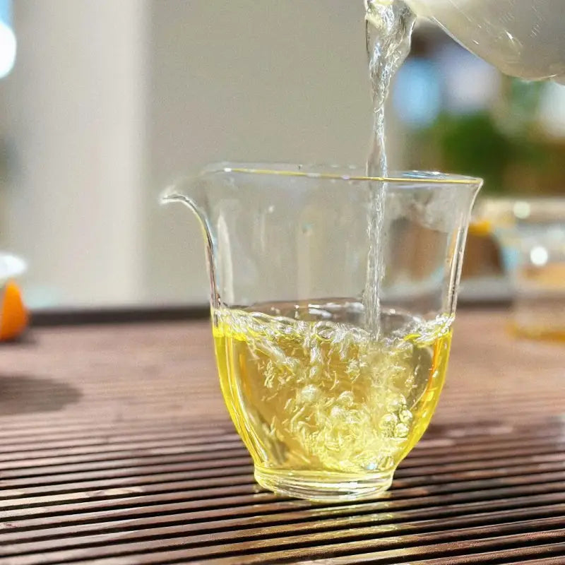 Clear glass pitcher being filled with liquid showcasing Bingdao Lao Zhai Raw Pu-erh 2024