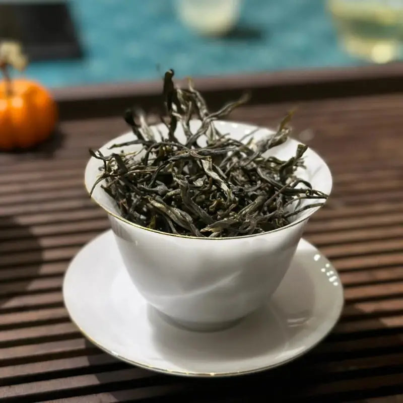 White teacup filled with dried tea leaves for Bingdao Lao Zhai Raw Pu-erh 2024