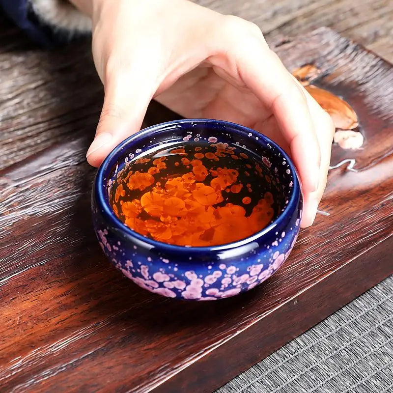 Blue ceramic teacup with orange liquid from Blossom Jian Zhan inspired by spring petals