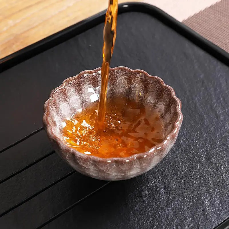 Tea being poured into a decorative bowl showcasing jian zhan with crackled minerals and glossy crystal glaze