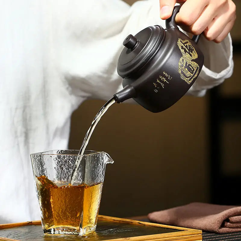 Black Celestial Script Yixing Zisha Teapot pouring tea showcasing handcrafted zisha clay artistry