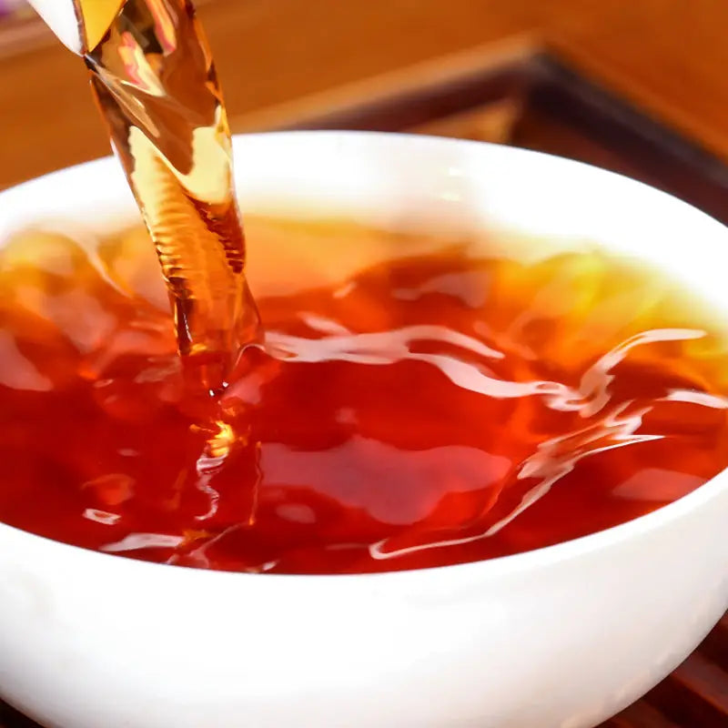 Amber liquid pouring into a white bowl for Cha Hua Shi Pu’er Tea Leave, perfect for teapots and tea sets