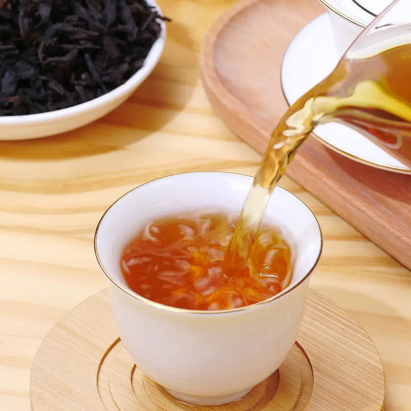 Tea being poured into a white and gold teacup from a elegant tea set with Cinna Mon Rock Tea Leaves