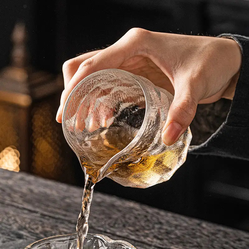 Textured glass pitcher pouring liquid, ideal for handcrafted glass tea and cloud mist textured gongfu tea setups