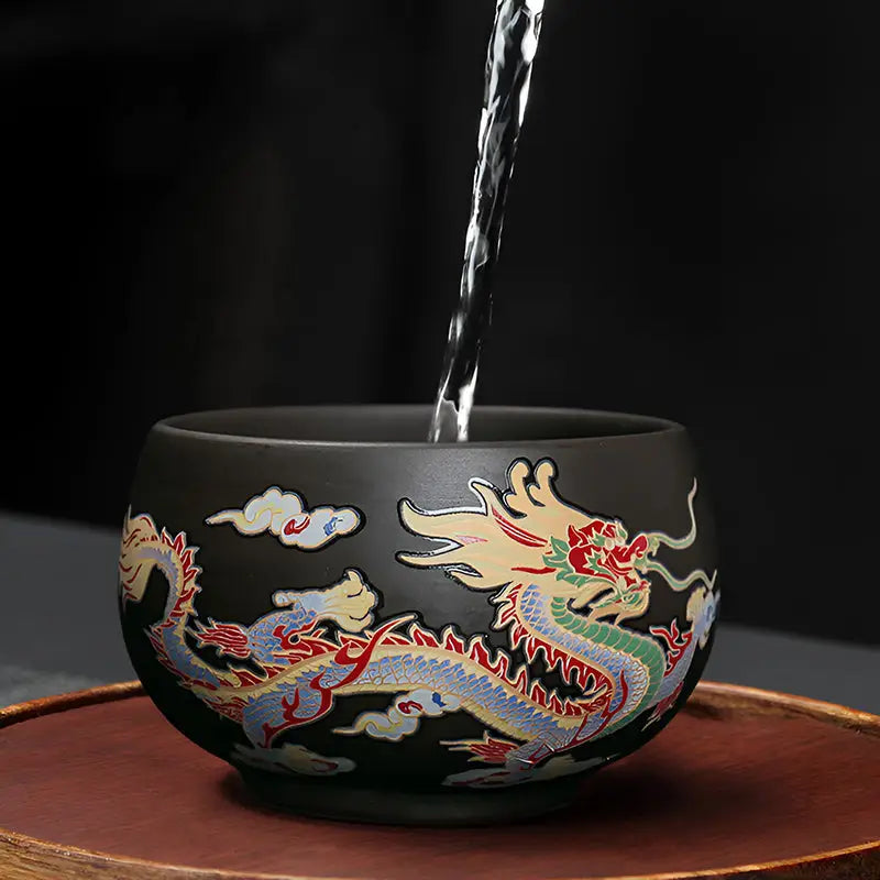 Black yixing zisha tea cup with colorful dragon design for tea ritual drinking