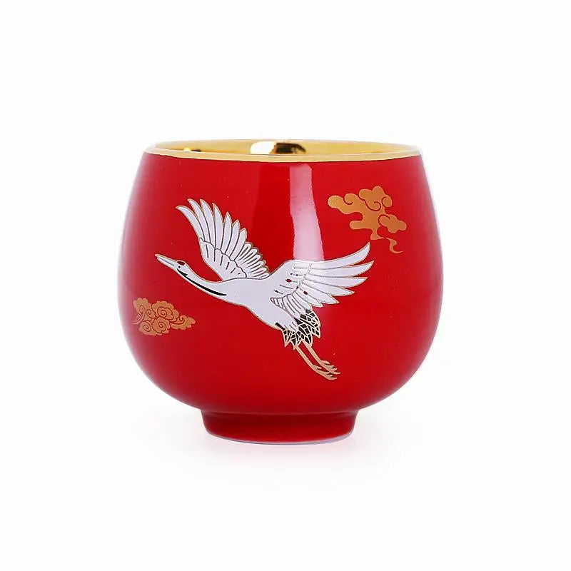Red ceramic jian zhan cup with flying white crane and gold trim design
