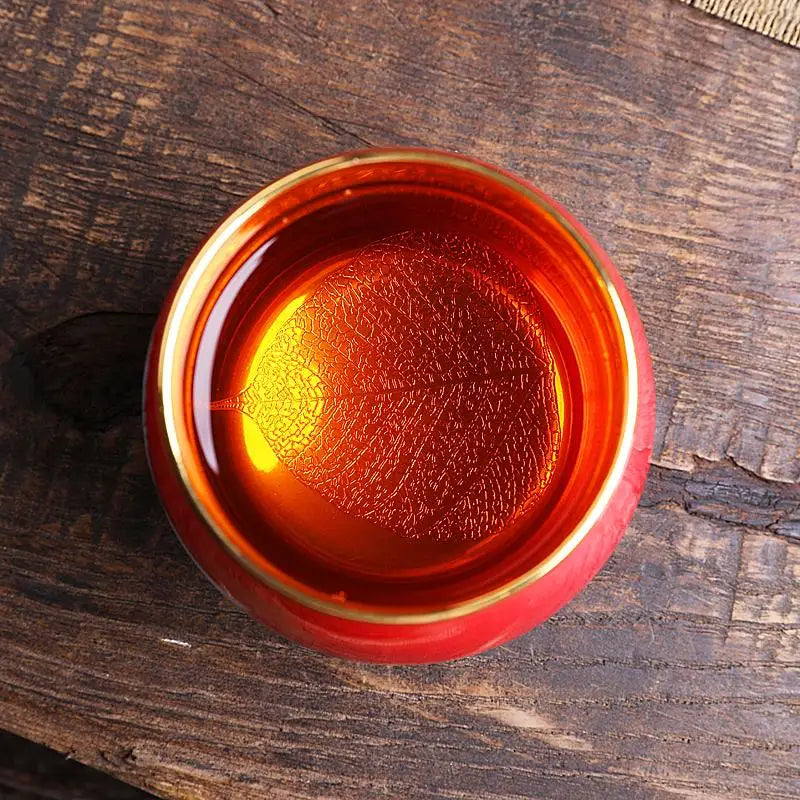 Red and gold teacup with leaf pattern showcasing Jian Zhan style and flying white crane design