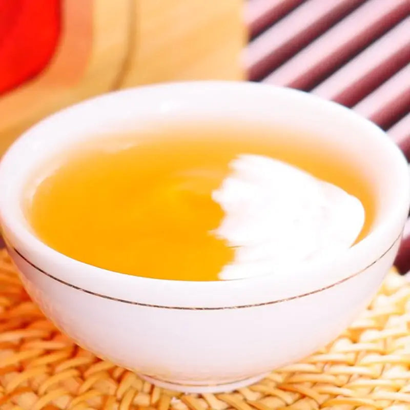 White teacup with golden liquid from Da Jin Zhong Black Tea Leaves, perfect for tea sets