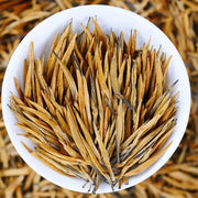 Golden needle tea leaves for Da Jin Zhong Black Tea displayed with teapots and mugs