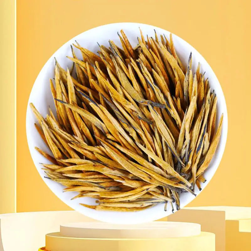Golden tea leaves in a white bowl for Da Jin Zhong Black Tea Leave with teapots and mugs