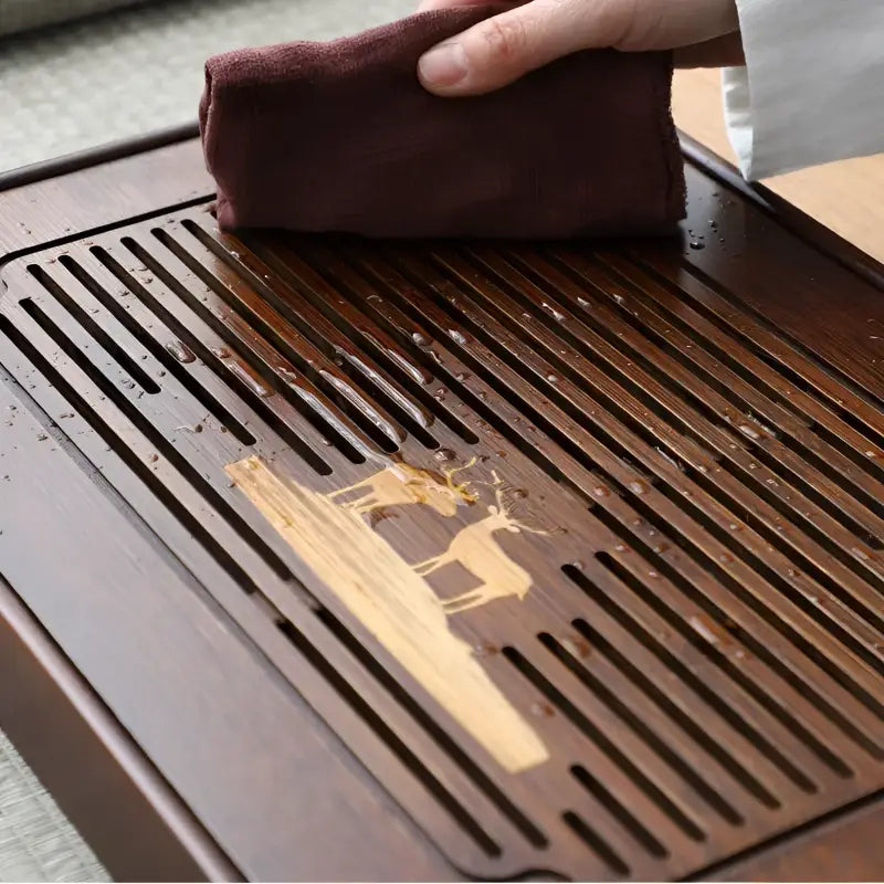 Deer Whisper bamboo gongfu tea tray with deer inlay being wiped for elegant tea service