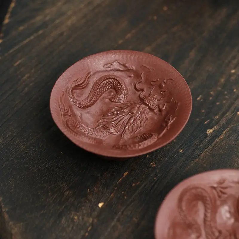 Round reddish-brown Dragon Spirit teacup with intricate dragon relief design