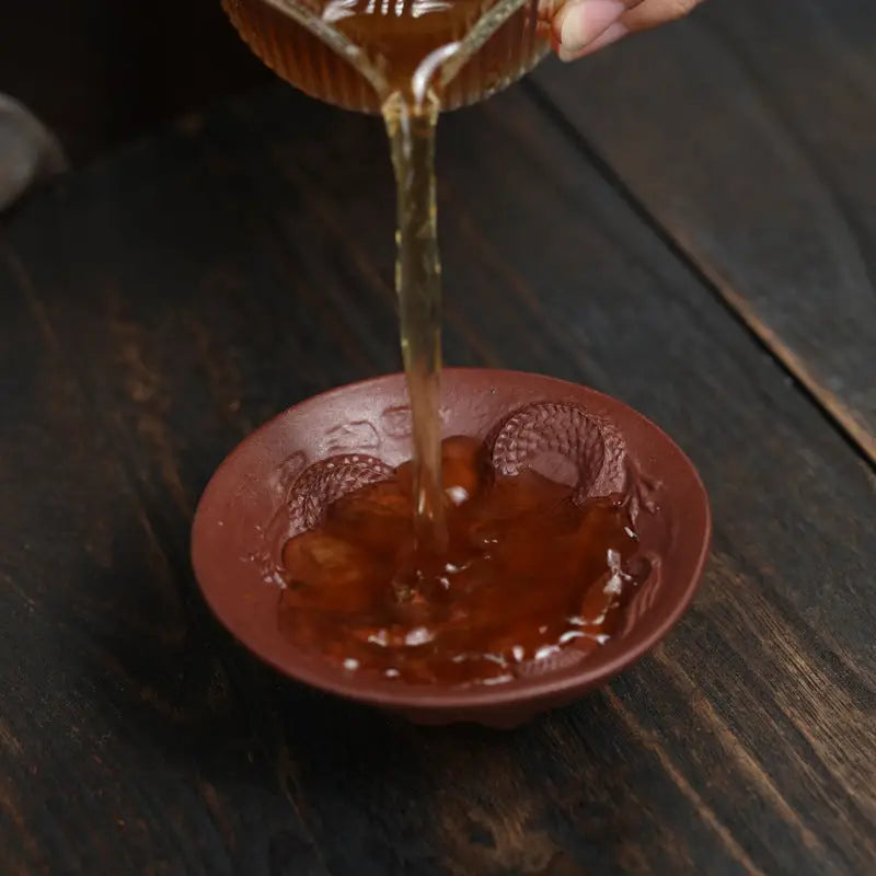 Tea being poured into a Dragon Spirit teacup with dragon embossing, showcasing elegance