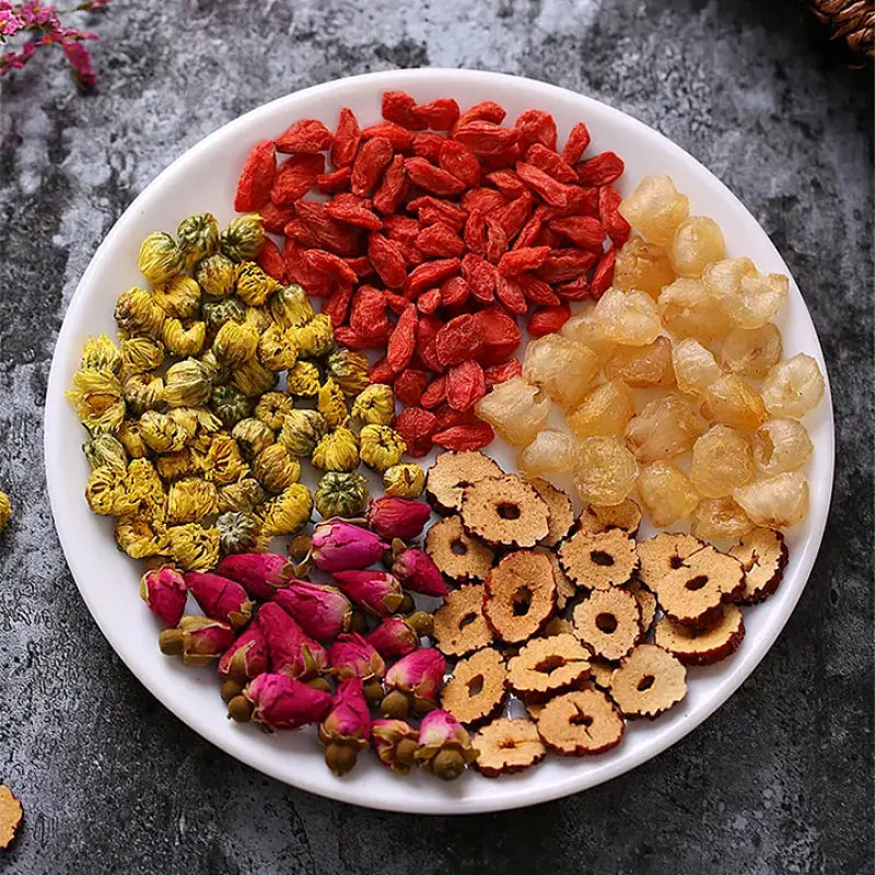 Assorted dried ingredients on a plate for herbal tea that alleviates menstrual pain and promotes blood circulation