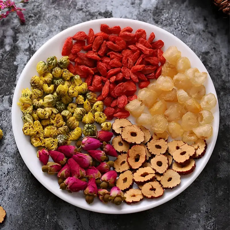 Assorted dried ingredients on a plate for herbal tea that alleviates menstrual pain and promotes blood circulation