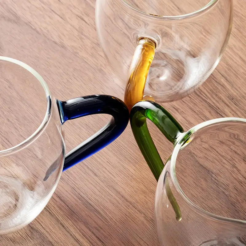 Three clear handblown glass cups with colored handles for Eagle Beak tea in high-borosilicate glass