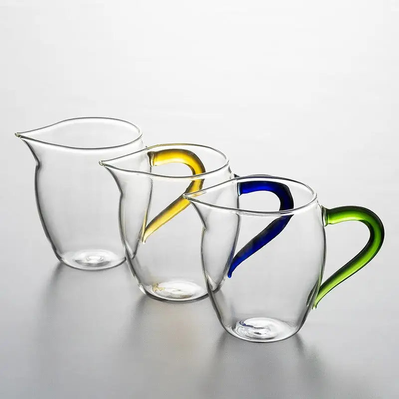 Three handblown glass pitchers with colored handles, perfect for Eagle Beak tea brewing
