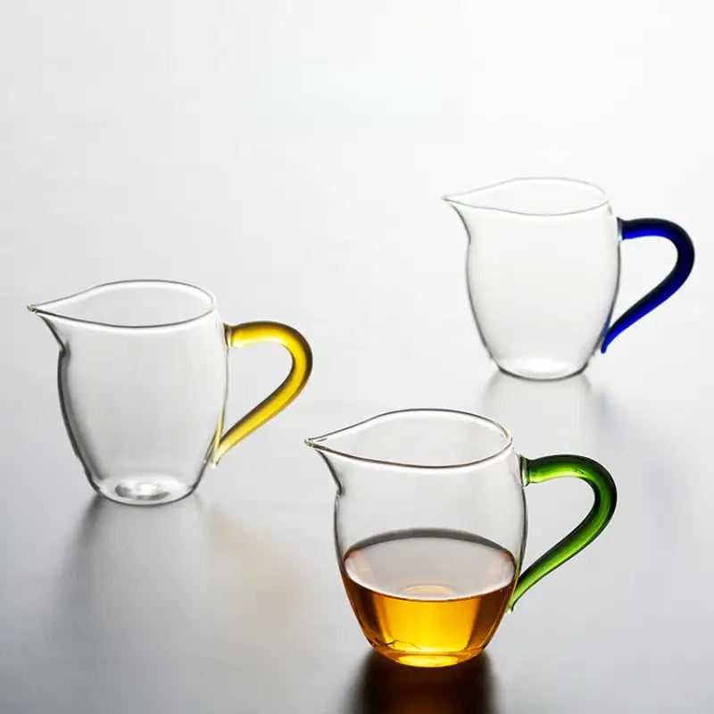 Three handblown high-borosilicate glass pitchers with colorful handles for Eagle Beak tea