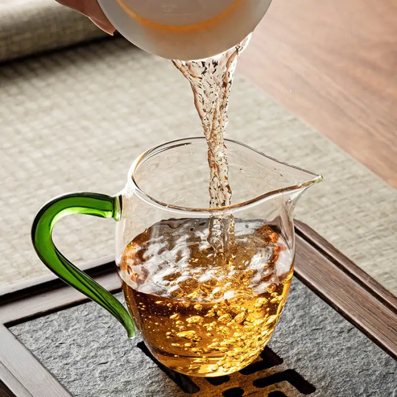 Glass pitcher with green handle filling Eagle Beak handblown high-borosilicate glass