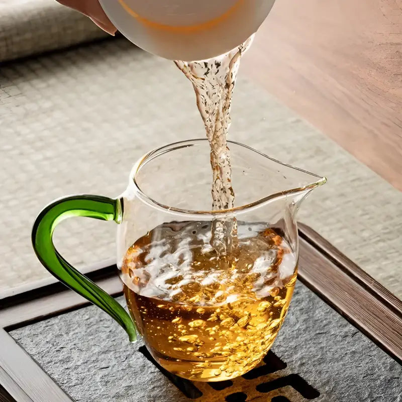 Glass pitcher with green handle filling Eagle Beak handblown high-borosilicate glass