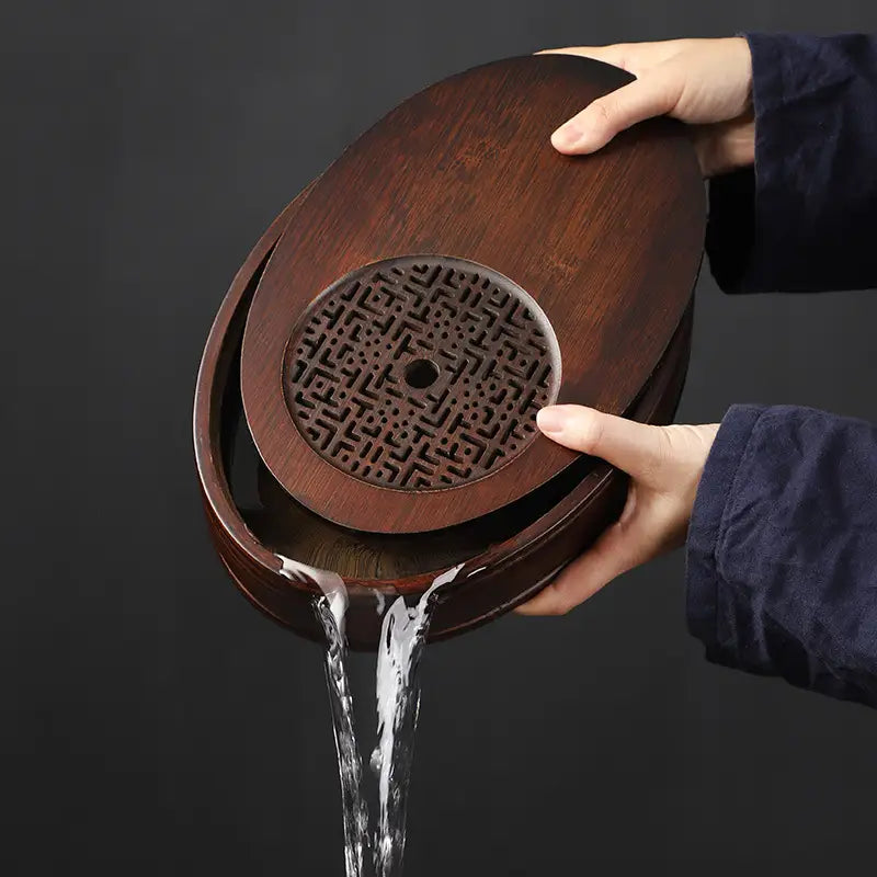 Wooden tea tray with water pouring out, showcasing Echo of Stillness oval bamboo gongfu tray