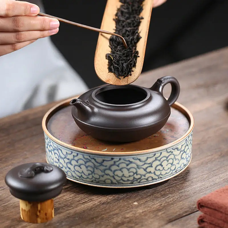 Brown Yixing Zisha teapot Eclipse being filled with tea for authentic tea brewing