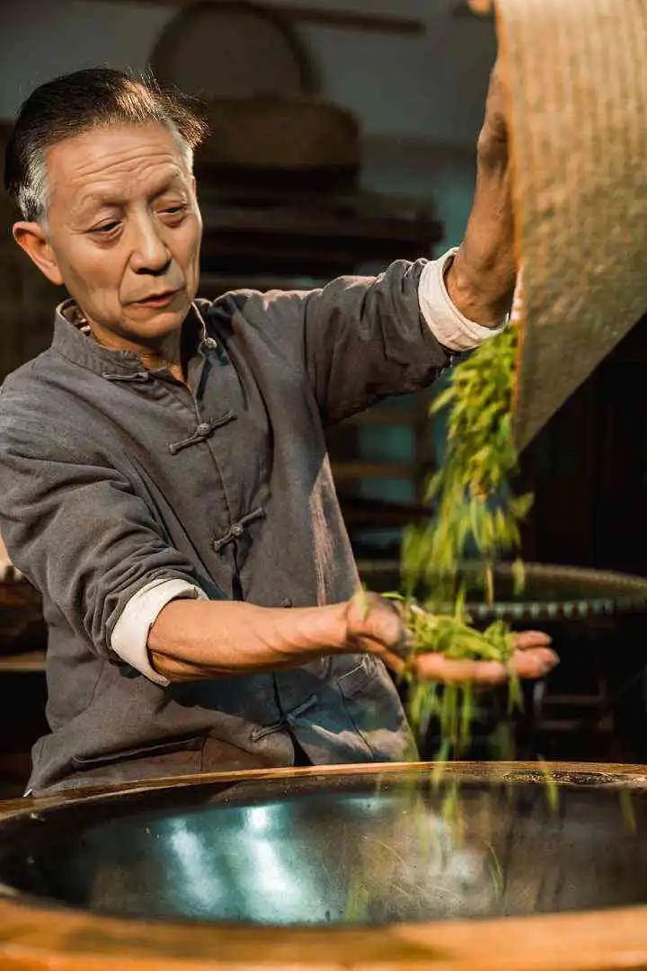 Elderly man processing tea leaves.
