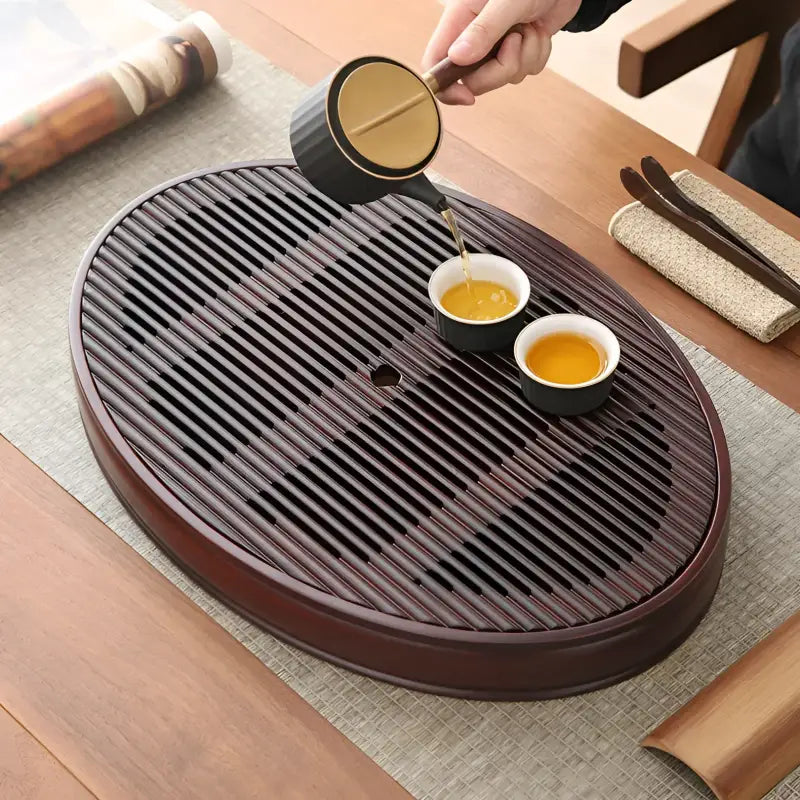 Flowing Zen oval bamboo tea tray with tea being poured, perfect for Gongfu tea brewing