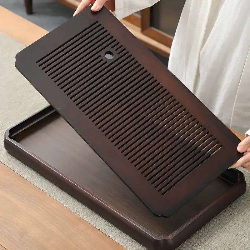 Dark brown wooden tea tray with slotted top for Gongfu tea brewing and bamboo gongfu setups