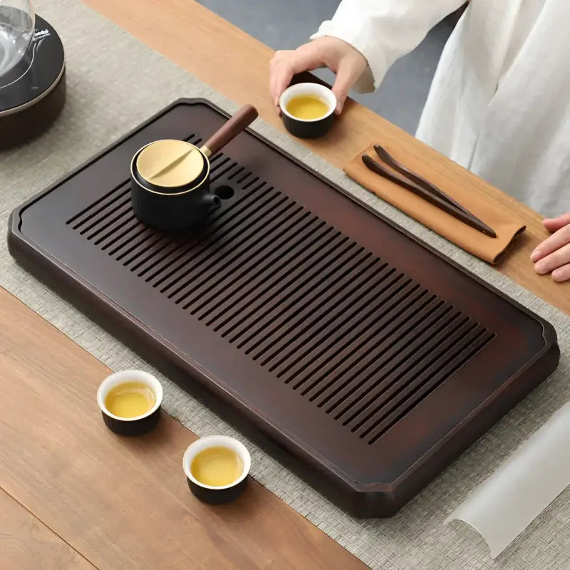 Dark wooden tea tray with slotted surface for Gongfu tea and bamboo Gongfu brewing