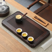 Dark wooden tea tray with tea set for gongfu tea brewing and bamboo gongfu presentation