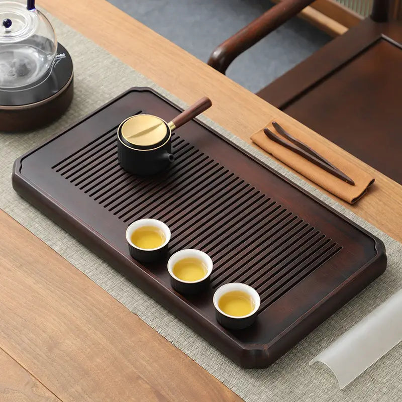 Dark wooden tea tray with tea set for gongfu tea brewing and bamboo gongfu presentation
