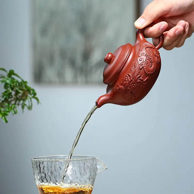Reddish-brown teapot pouring liquid from Flying Dragon Yixing Zisha handcrafted dragon