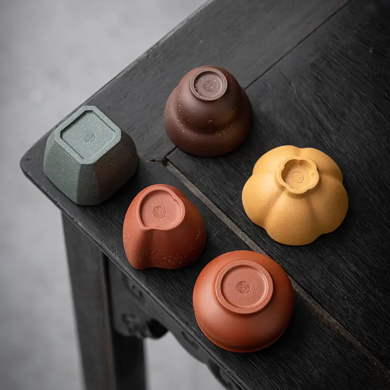 Assorted ceramic teacups from Forest Dew Tea Set showcasing Yixing Zisha craftsmanship