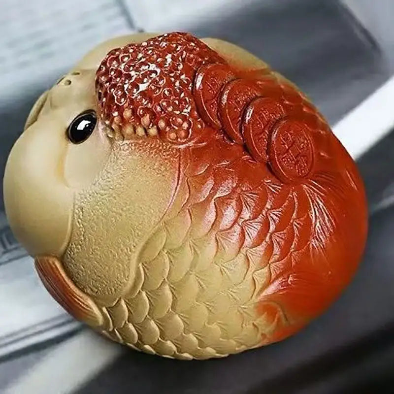 Ceramic goldfish figurine with coins as a feng shui tea pet for good luck and wealth