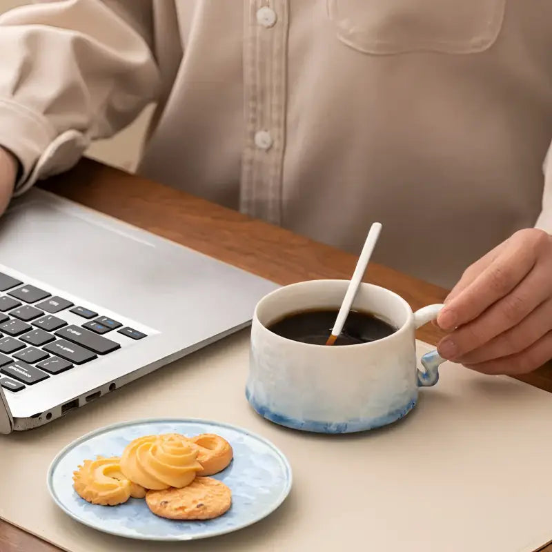 Blue-rimmed ceramic coffee cup with tenmoku glaze and matching saucer for cozy mornings