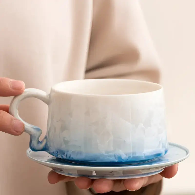 White and blue textured ceramic coffee cup with tenmoku glaze and matching saucer
